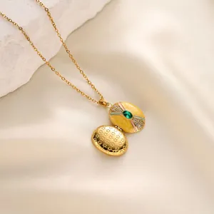Detailed view of a gold-plated oval locket necklace with yellow enamel and green gem.