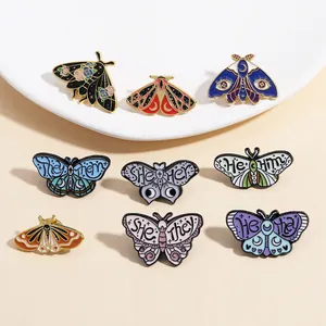 Close-up detail of colorful butterfly and moth enamel pins featuring pronoun text designs