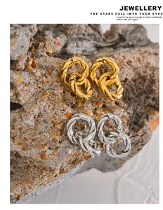 Detail showing textured twisted double hoop earrings in gold and silver finishes.