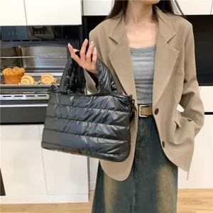 Stylish black quilted puffer handbag held by a model in a casual indoor setting.