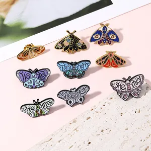 Artistic collection of colorful moth and butterfly enamel pins with gender pronouns