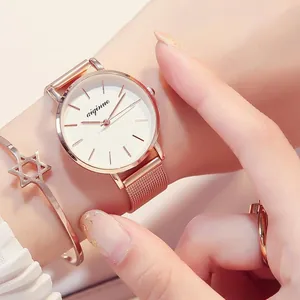 Detail view of an elegant rose gold women's quartz watch with a Milanese mesh strap on wrist