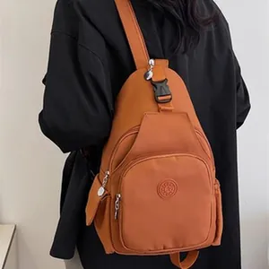 Back view of a person wearing a large orange sling bag with multiple zip pockets