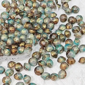 Macro view of 8x10mm saucer-shaped glass beads with vintage gold and turquoise textures