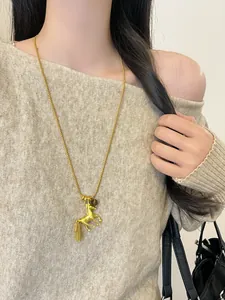 Elegant long gold necklace with a galloping horse pendant worn over a beige sweater