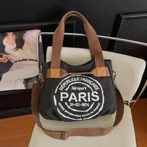Detailed view of black canvas tote bag with Paris airport print on a white chair