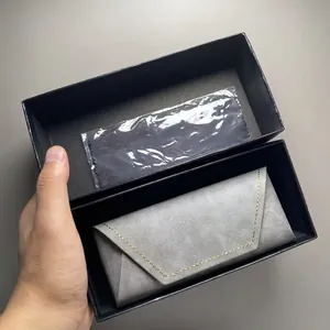 Detail van grijze opvouwbare driehoekige brillenkoker in zwarte geschenkdoos met doek