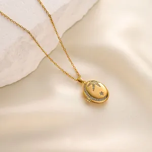 Close-up of gold celestial oval locket necklace with moon and star zircon details