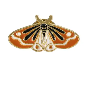 Vintage enamel moth brooch pin featuring orange and black wing details on white background