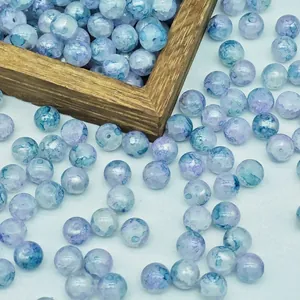 Close-up of water-dyed glass beads with blue and purple ink-wash patterns for DIY jewelry.