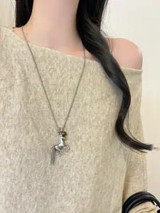 Detail view of a silver horse pendant necklace with chain tassel on a model.