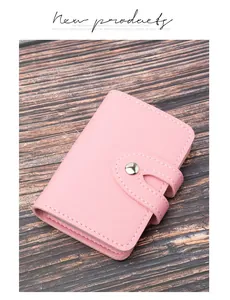 Primo piano di un porta carte in pelle rosa con chiusura a scatto su base in legno