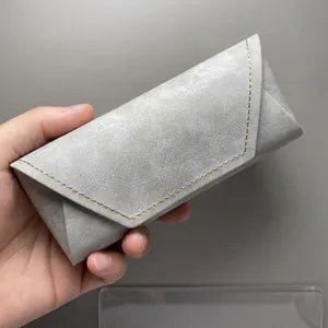 Close-up van een premium grijze marmeren inklapbare brillenkoker met gele stiksels