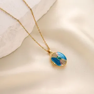 Close-up detail of a gold-toned enamel locket necklace featuring a central green gemstone.