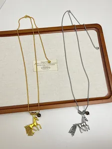 Detail view of gold and silver metal horse pendant necklaces with tassels on long chains