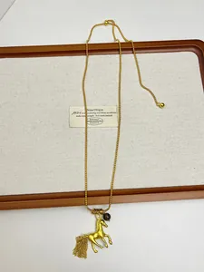 Detailed close-up of an elegant gold horse pendant necklace on a white jewelry tray.