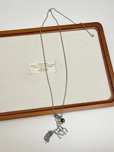 Macro detail of a silver metal horse pendant necklace with a tassel on a wooden tray