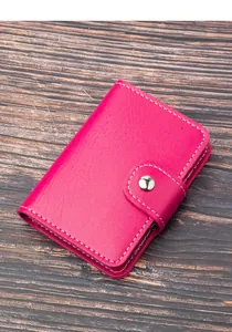 Primo piano di un porta carte in pelle fucsia con cuciture bianche e bottone.
