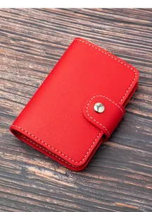 Primo piano di un elegante portacarte in pelle rossa con cuciture bianche e chiusura metallo.