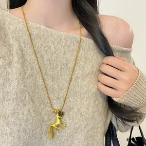 Elegant gold-plated horse pendant long necklace with tassel detail on beige sweater