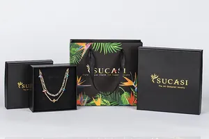 Premium black jewelry packaging set including gift boxes and a floral paper bag
