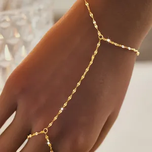 Dettaglio di un elegante bracciale a mano in catena dorata con anello da donna