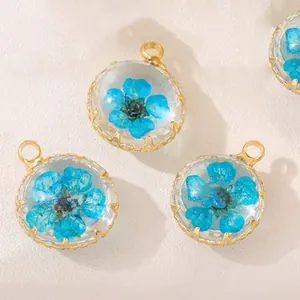 Macro view of handmade round glass pendant with a real blue dried flower and gold frame