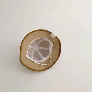 Interior detail of a camel baby bucket hat featuring a white mesh lining and soft chin strap