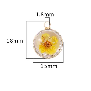Macro detail of 15mm round glass pendant with yellow dried flower and gold rim.