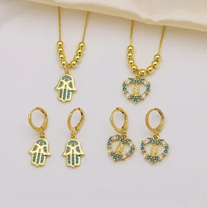 Detail of 18K gold plated Hamsa and Virgin Mary heart jewelry sets with blue zirconia