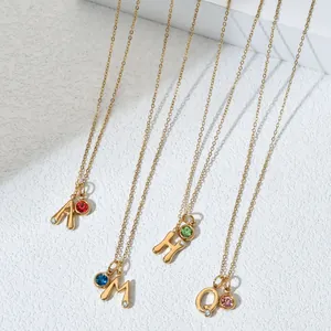 Close-up detail view of gold stainless steel initial necklaces with colorful birthstones