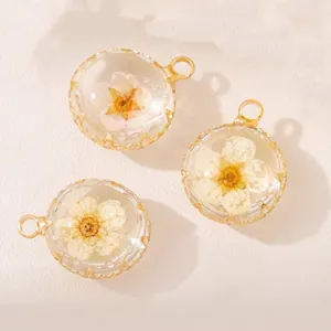 Close-up of round glass pendants with delicate dried white flowers and gold frames