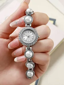 Gros plan d'une montre à quartz argentée avec perles blanches et lunette en cristaux