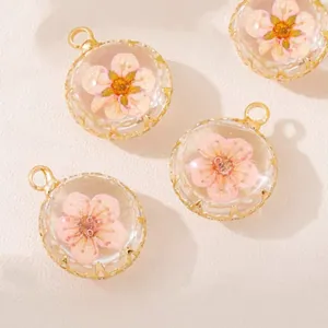 Close-up of transparent round glass pendants with pink dried flowers for DIY jewelry