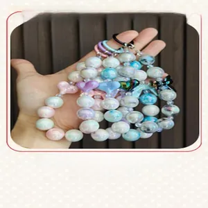 Detailed view of colorful electroplated beaded keychains with bow charms held in hand