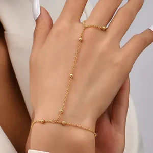 Elegante bracciale a catena per dita placcato in oro con perline su una mano di donna.