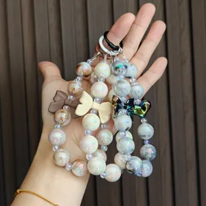 Close-up view of colorful iridescent beaded keychains with bows held against wooden background