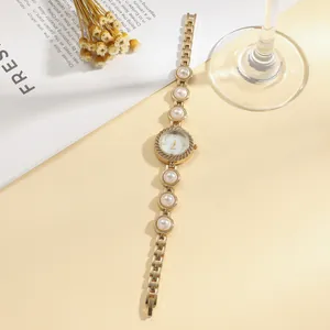 Detail view of elegant women's gold quartz watch featuring integrated pearl bracelet links