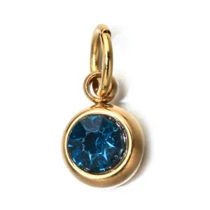Detail shot of a round gold stainless steel pendant with a blue faceted birthstone