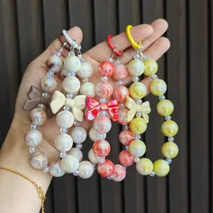 Detailed close-up view of four candy-colored beaded bow phone charms and decorative keychains