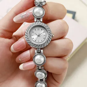 Élégante montre à quartz en argent avec bracelet en perles et strass tenue à la main