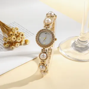 Close-up of elegant women's gold quartz watch with a stylish pearl bracelet strap