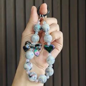 Detailed view of an electroplated beaded keychain with iridescent bow and heart charms.