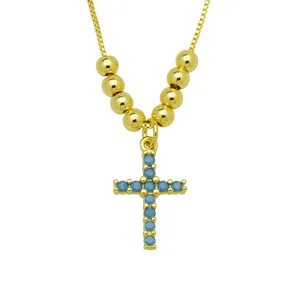 Detail of 18K gold-plated necklace with blue zircon cross pendant and polished gold beads.