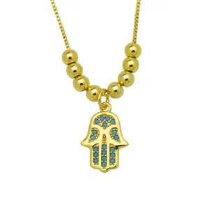 Macro detail of 18K gold-plated Hamsa hand necklace pendant with blue cubic zirconia