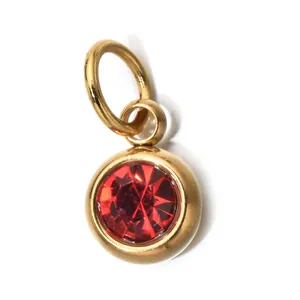 Close-up detail of a gold stainless steel round pendant with a vibrant red birthstone crystal