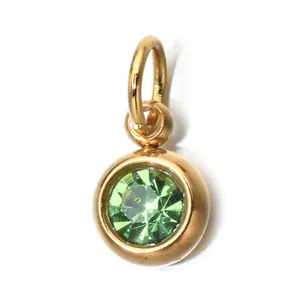 Macro view of a round gold-plated stainless steel pendant with a green faceted birthstone