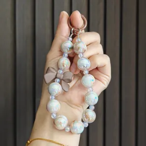 Detailed view of pearlescent beaded keychain with a matte brown bow charm accessory