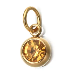 Detailed close-up of a gold-plated stainless steel pendant featuring an amber birthstone charm