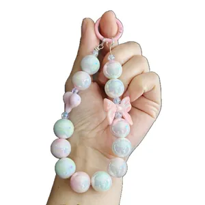 Handheld display of a cute iridescent beaded keychain with a pink bow and pearls